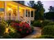 Illuminated front porch with rose bushes, green shrubbery and a stone walkway to the front steps at 48 Falling Oak Ct, Clayton, NC 27520