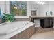 Corner garden tub with large window view, tile floors, and vanity at 5004 Clowser Minnow Ct, Wake Forest, NC 27587