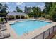 Community pool featuring lounge chairs, tables with umbrellas, and a bath house surrounded by a metal fence at 5004 Clowser Minnow Ct, Wake Forest, NC 27587