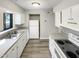 Well-lit kitchen showcasing white cabinets, stainless steel sink, and updated flooring at 5078 Flint Ridge Pl, Raleigh, NC 27609