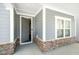 Covered front porch with gray siding, stone accents, and an open front door at 608 Cormiche Ln, Wake Forest, NC 27587