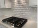 Modern kitchen featuring a smooth gas cooktop, white subway tile backsplash, and clean quartz countertops at 633 Hardin Hill Ln, Knightdale, NC 27545