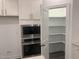 Walk-in pantry providing ample storage and shelving, located next to stainless steel microwave and oven at 633 Hardin Hill Ln, Knightdale, NC 27545