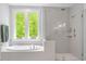 Spa bathroom featuring soaking tub with picture window, and glass enclosed shower with gray tile at 66 Romie Ct, Pittsboro, NC 27312