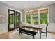 Bright dining room with wood table, bench seating, and scenic views from multiple windows at 66 Romie Ct, Pittsboro, NC 27312
