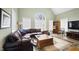 Comfortable living room featuring vaulted ceiling, large arched windows, and a plush leather couch at 1004 Dunleigh Dr, Burlington, NC 27215