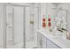 Bright bathroom featuring dual sinks, quartz countertop, chrome faucets, and glass-enclosed shower with shelves at 1047 Winding Spring Dr, Mebane, NC 27302