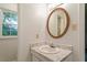 Bathroom vanity with a marble-style top, decorative mirror, neutral walls and window at 1217 Manassas Ct # H, Raleigh, NC 27615