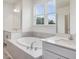 Bright bathroom featuring a drop-in bathtub with a view and double vanities at 149 Whimbrel Ct, Lillington, NC 27546