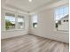 Bright living room featuring light wood floors, white walls, and three large windows at 149 Whimbrel Ct, Lillington, NC 27546