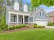 Charming blue home featuring a manicured lawn, stone accents, and a welcoming covered front porch at 1620 Hasentree Villa Ln, Wake Forest, NC 27587