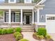 Inviting front porch with stone accents, white columns, and lush landscaping creating a warm entrance at 1620 Hasentree Villa Ln, Wake Forest, NC 27587