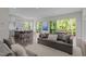 Open-concept living room with hardwood floors, gray sofa, and a view of the outdoor deck through sliding glass doors at 1620 Hasentree Villa Ln, Wake Forest, NC 27587