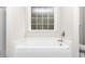 Bright bathtub area featuring a frosted window for privacy and nice natural lighting at 186 N Ashe Ave, Dunn, NC 28334