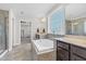 Bright bathroom with tiled floor, soaking tub beneath large window, and separate glass-enclosed shower at 2008 Campana Dr, Raleigh, NC 27603