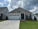 Charming single-story home featuring a two-car garage, manicured lawn, and neutral siding with stone accents at 206 Jetson Creek Way, Youngsville, NC 27596