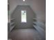 Attic storage area with a single window and white built in shelving and light colored walls at 2590 Silas Peak Ln, Apex, NC 27523