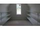 Bright attic with window, open shelving for storage, and unfinished floors at 2590 Silas Peak Ln, Apex, NC 27523