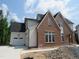 Two-story new home with brick and white siding, three car garage, and unfinished landscaping at 2590 Silas Peak Ln, Apex, NC 27523