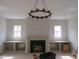 Open living room boasts a fireplace with built-ins and stylish chandelier lighting at 2590 Silas Peak Ln, Apex, NC 27523