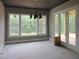 Living room with abundant natural light from large windows and french doors, complemented by a modern chandelier at 2590 Silas Peak Ln, Apex, NC 27523