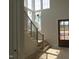 Light-filled staircase with wood railing and black metal balusters next to tall windows at 2590 Silas Peak Ln, Apex, NC 27523