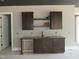Contemporary wet bar featuring dark cabinetry, sleek hardware, and stylish open shelving at 2590 Silas Peak Ln, Apex, NC 27523