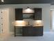 Dark gray wet bar featuring ample lighting and cabinets offers a convenient place for refreshments at 2590 Silas Peak Ln, Apex, NC 27523