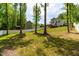Green backyard featuring mature trees, a wooden deck, and ample space for outdoor activities at 27 Ashley Woods Ct, Clayton, NC 27527