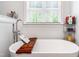 Relaxing bathroom featuring a soaking tub with wooden tray, stylish faucet, and a window view at 27 Ashley Woods Ct, Clayton, NC 27527
