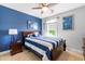 Bedroom with blue accent wall, ceiling fan, and a large bed with blue and white striped bedding at 27 Ashley Woods Ct, Clayton, NC 27527