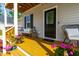 Charming front porch with seating, black door and black shutter accents, and colorful blooms at 27 Ashley Woods Ct, Clayton, NC 27527