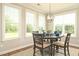 Bright dining area with wood table set, modern light fixture, and three large windows overlooking the lush green backyard at 3017 Dog Rose Dr # 169, Durham, NC 27703