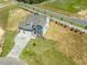 Aerial view of a modern home featuring stone accents, a three-car garage, and a well-manicured lawn at 33 Celtic Ln, Lillington, NC 27546
