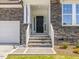 Close-up of front entryway with stone facade, white railings, and a dark front door at 33 Celtic Ln, Lillington, NC 27546
