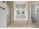 Bright bathroom featuring a tub under a window and a glass-enclosed shower stall at 4418 Gallatree Ln, Raleigh, NC 27616