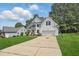 Inviting white two-story home with a long driveway, basketball hoop, and green lawn at 4418 Gallatree Ln, Raleigh, NC 27616