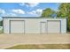 Functional white metal garage featuring two roll-up doors, one walk-in door, and a basketball hoop for recreation at 6042 Elliott Bridge Rd, Linden, NC 28356