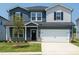 Charming two-story home with a well-manicured lawn, two-car garage, and a mix of horizontal and shake siding at 659 White Birch Ln, Angier, NC 27501