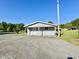 Detached garage with gravel driveway, set against a backdrop of lush greenery and a clear blue sky at 668 Surl Mount Tirzah Rd, Timberlake, NC 27583
