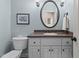 Charming bathroom features a powder blue wall, white cabinets, granite counter and round mirror at 7400 Portpatrick Ct, Wake Forest, NC 27587