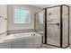 Bathroom featuring a tub, shower, and a glass block window at 7400 Portpatrick Ct, Wake Forest, NC 27587