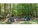 Scenic stone fire pit nestled in a wooded area, featuring Adirondack chairs for relaxing evenings outdoors at 7400 Portpatrick Ct, Wake Forest, NC 27587