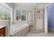 Bright bathroom featuring a soaking tub beneath a window and a glass-enclosed shower at 7405 Pine Summit Dr, Fuquay Varina, NC 27526