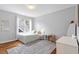Cozy bedroom with light gray walls, wood floors, a gray area rug and a bright window with sheer curtains at 811 E Lane St, Raleigh, NC 27601