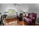 Comfortable bedroom with hardwood floors, ceiling fan, two comfy recliners, and a window with a wooded view at 1005 Stuart Dr, Mebane, NC 27302