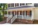 Inviting front porch with brick foundation, white railings, and ample seating at 1005 Stuart Dr, Mebane, NC 27302
