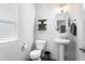 Contemporary half bathroom with a pedestal sink, round mirror, and a sleek black storage shelf at 1009 Haynoke Dr, Graham, NC 27253