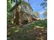 Side and back exterior view with brick and siding and a sloped yard with some mature trees at 1102 Parkwood Dr, Siler City, NC 27344