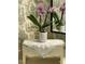 Close-up of a small bench with flowers and a delicate doily in a wallpapered bathroom at 112 Hilton Ave, Durham, NC 27707